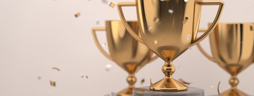 Golden trophy award with falling confetti on grey background. copy space for text. Competition winner prize. 3d rendering.