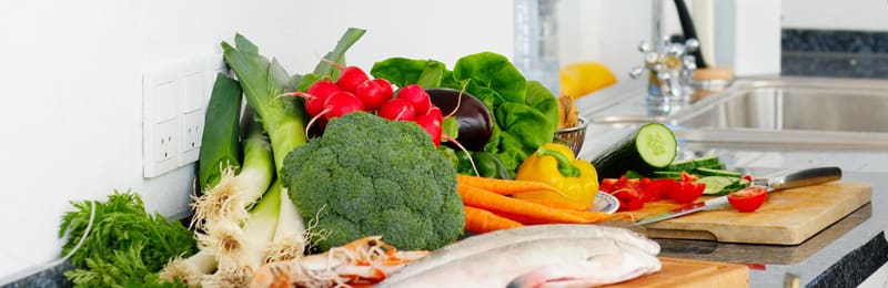 a kitchen counter topped with lots of fresh vegetables